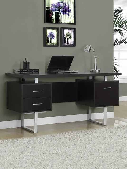 Translation missing: en.A solid mango wood study desk with brown finish and silver metal legs, featuring drawers and a space for a laptop, placed against a wall with framed pictures above it